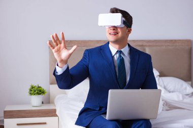 Yatak odasında sanal gerçeklik kulaklığı takan bir iş adamı.