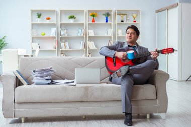 Evde gitar çalan bir iş adamı.