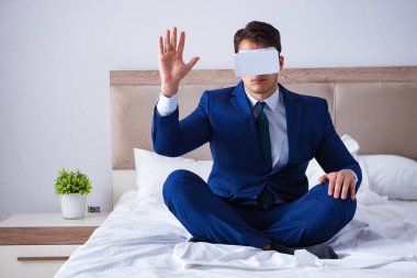 Yatak odasında sanal gerçeklik kulaklığı takan bir iş adamı.