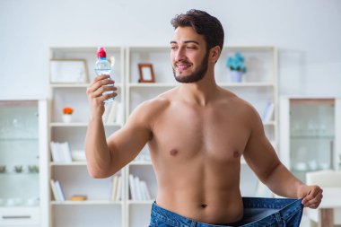 Kilo verme konseptinde büyük beden pantolon giyen bir adam.