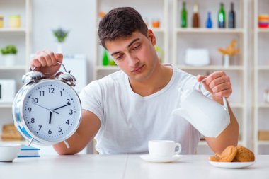 Çalar saati olan bir adam kahvaltıda uyuyakalıyor.