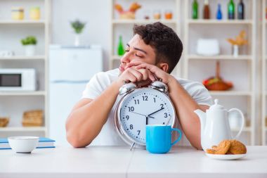 Çalar saati olan bir adam kahvaltıda uyuyakalıyor.
