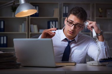 İş adamı telefonda konuşuyor ve ofiste sigara içiyor.