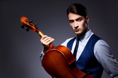 Genç adam karanlık odada çello çalıyor.