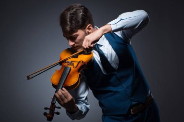 Genç adam karanlık odada keman çalıyor.