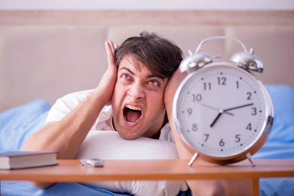 Homme au lit frustré souffrant d'insomnie avec un cloc d'alarme — Photo