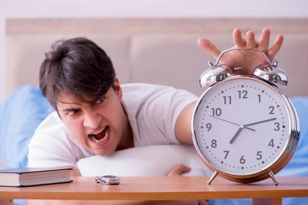 Hombre en la cama frustrado sufriendo de insomnio con un zueco de alarma — Foto de Stock