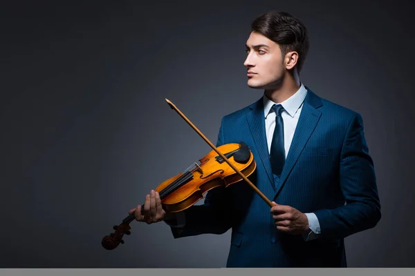 Young man playing violin in dark room — Stock Photo, Image