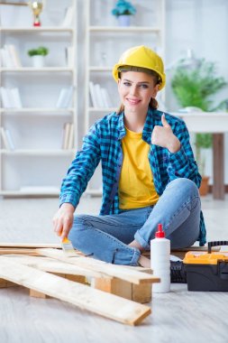 Tamirci kadın marangoz ahşap döşemeleri kesiyor.