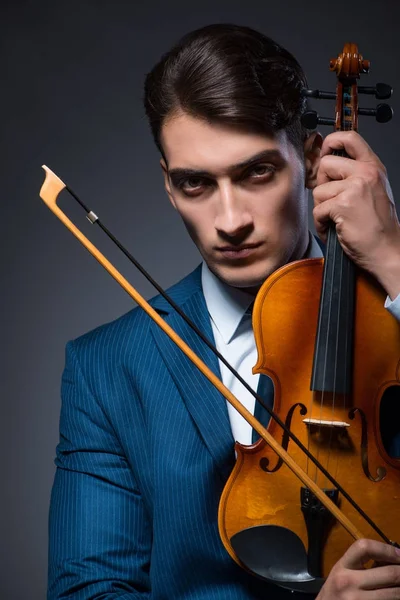 Jovem tocando violino no quarto escuro — Fotografia de Stock