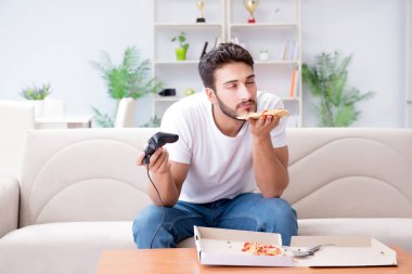 Pizza yiyen adam evde yemek yiyor, dinleniyor.