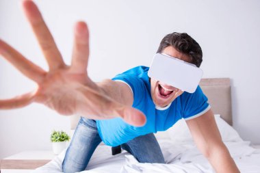 Yatakta sanal gerçeklik başlığı takan genç bir adam.