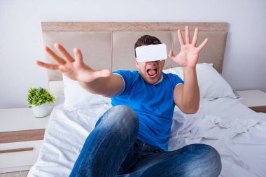 Yatakta sanal gerçeklik başlığı takan genç bir adam.
