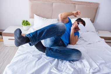 Yatakta sanal gerçeklik başlığı takan genç bir adam.