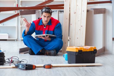 İnşaatta defter planlama yapan genç bir marangoz.