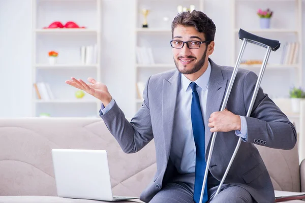 Empresario con muletas y pierna rota en casa trabajando —  Fotos de Stock