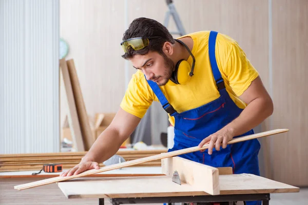 Genç bir marangoz dairesel testereyle odun kesiyor.