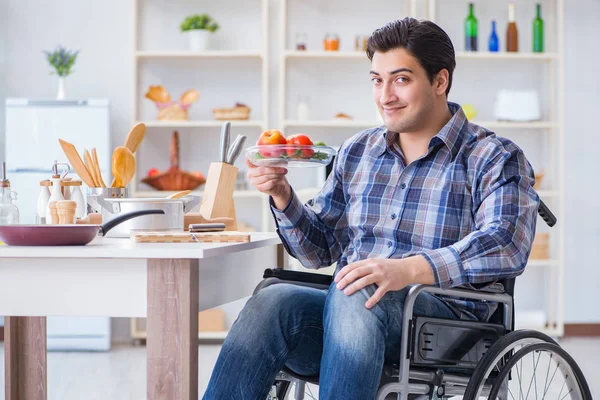 Genç engelli koca yemek salatası hazırlıyor.