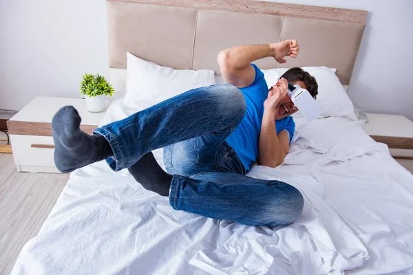 Yatakta sanal gerçeklik başlığı takan genç bir adam.