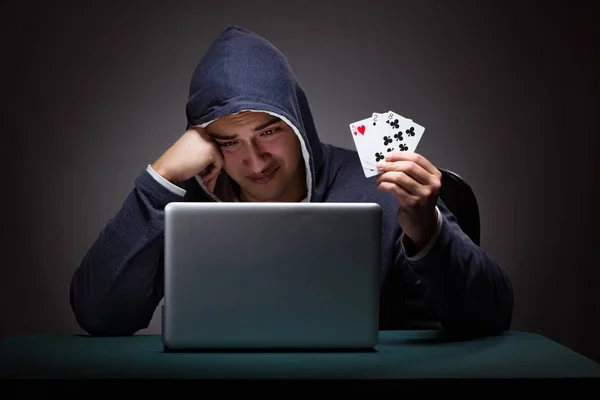 Joven con una sudadera con capucha sentado frente a una computadora portátil — Foto de Stock