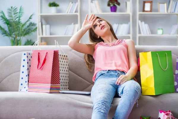 Jonge vrouw met boodschappentassen binnen op de bank — Stockfoto