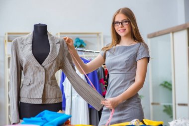 Atölyede çalışan genç bayan terzi yeni elbise üzerinde çalışıyor.