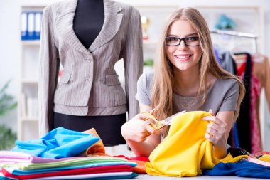 Atölyede çalışan genç bayan terzi yeni elbise üzerinde çalışıyor.