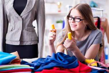 Atölyede çalışan genç bayan terzi yeni elbise üzerinde çalışıyor.