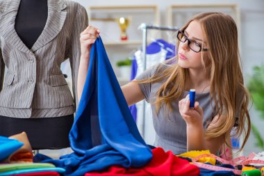 Atölyede çalışan genç bayan terzi yeni elbise üzerinde çalışıyor.