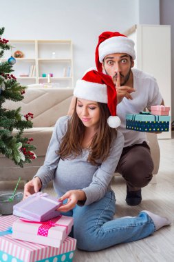 Genç aile Noel 'i kutlayan bir bebek bekliyor.