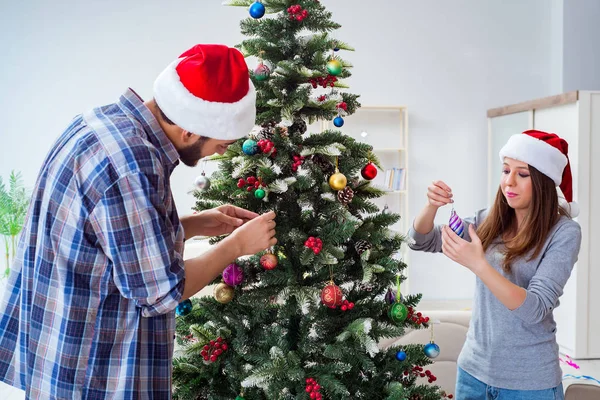 Genç aile Noel ağacını mutlu bir vesileyle süslüyor.