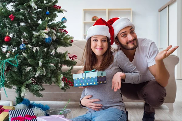 Mladá rodina očekává dítě oslavující Vánoce — Stock fotografie