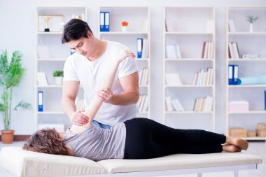 Genç doktor kayropraktik uzmanı kadın hastaya masaj yapıyor.