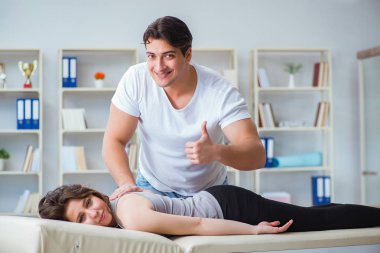 Genç doktor kayropraktik uzmanı kadın hastaya masaj yapıyor.
