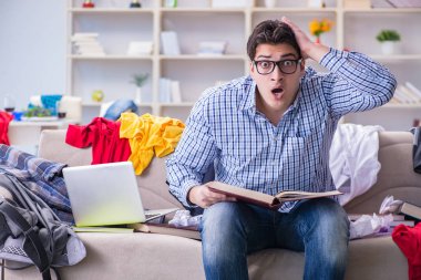 Genç adam dağınık bir odada çalışıyor.