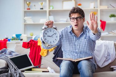 Genç adam dağınık bir odada çalışıyor.