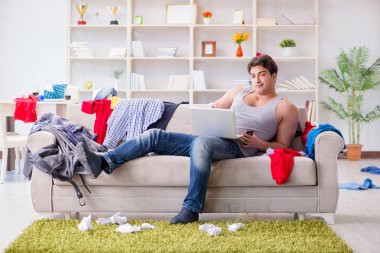 Genç adam dağınık bir odada çalışıyor.