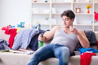 Dağınık bir odada alkol alan genç bir öğrenci.