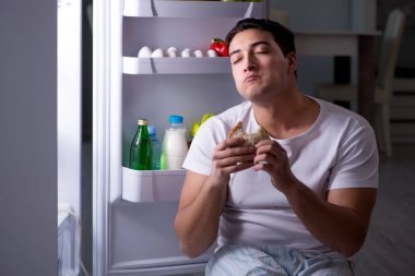 Buzdolabındaki adam gece yemek yiyor.