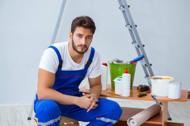 Tamirci, duvar kağıdıyla evde tadilat yapıyor.