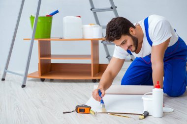 Tamirci, duvar kağıdıyla evde tadilat yapıyor.