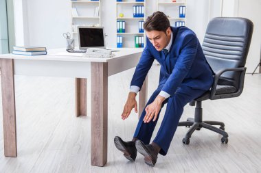 Genç işadamı iş yerinde spor yapıyor.