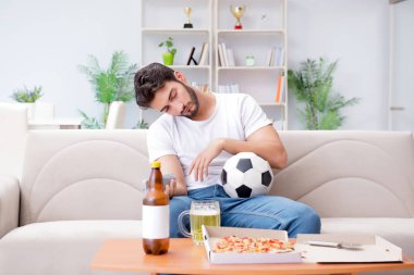 Pizza yiyen adam evde yemek yiyor, dinleniyor.