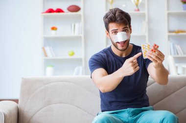 Genç adam estetik cerrahi burnundan sonra evde iyileşiyor.