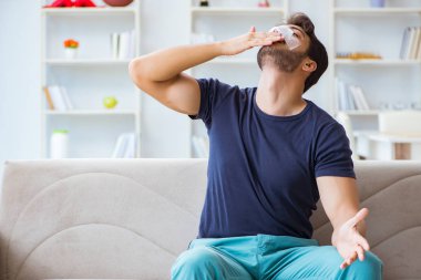 Genç adam estetik cerrahi burnundan sonra evde iyileşiyor.