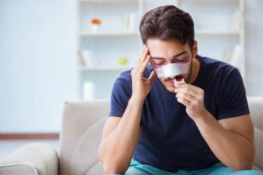 Genç adam estetik cerrahi burnundan sonra evde iyileşiyor.