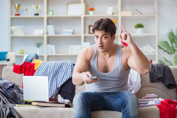 Genç adam dağınık bir odada çalışıyor.