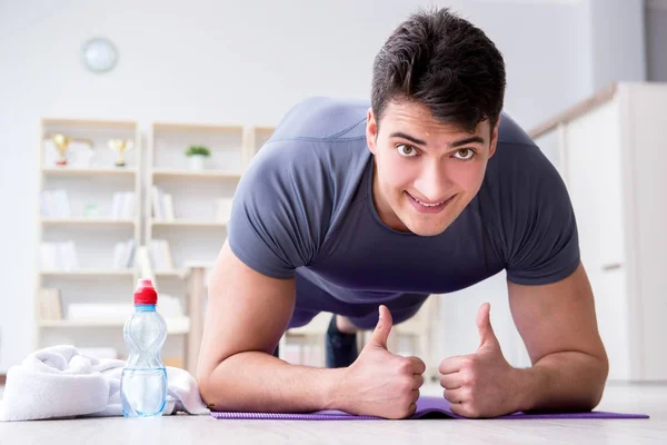 Joven haciendo ejercicio en casa en deportes y estilo de vida saludable con — Foto de Stock