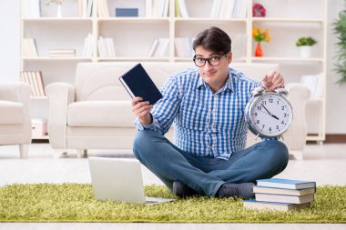 Genç yakışıklı adam evde yerde oturuyor.