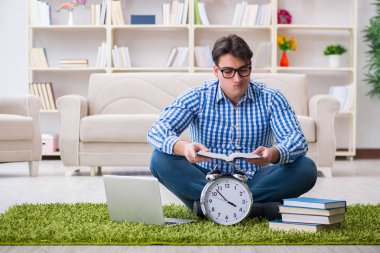 Genç yakışıklı adam evde yerde oturuyor.